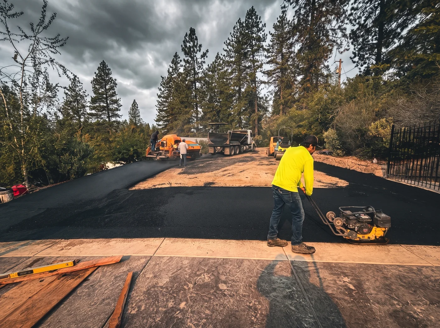 Crew compacting the edge of a driveway during asphalt installation